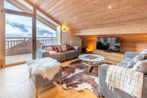 - un salon avec des canapés et une grande fenêtre dans l'établissement Etania 401 beautiful penthouse apartment in Meribel Morel, à Méribel