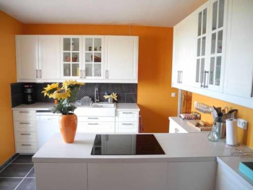 une cuisine avec des placards blancs et un vase de fleurs sur un comptoir dans l'établissement La Maison Alex, à Castelnau-de-Guers