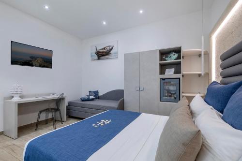 a bedroom with a bed and a couch and a desk at Hotel Soffio D'Estate in San Vito lo Capo