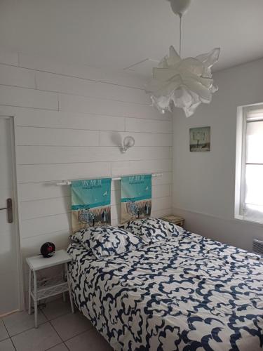 a bedroom with a bed with a blue and white comforter at Maison bord de mer in Asnelles