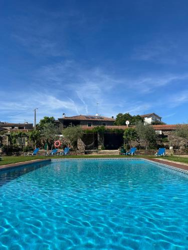 une grande piscine bleue avec des chaises et un bâtiment dans l'établissement Casa dos Araújos, à Frechas