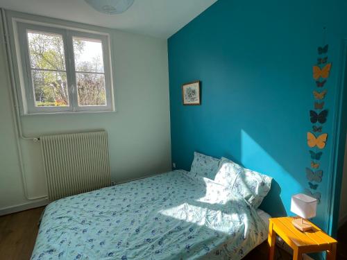 une chambre avec un lit aux murs bleus et une fenêtre dans l'établissement Chez Gilles et Anne, à Onzain