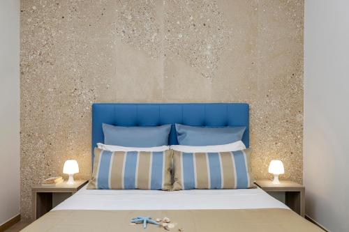 a bed with a blue headboard and two lamps at Hotel Soffio D'Estate in San Vito lo Capo