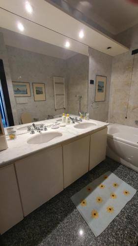 une salle de bain avec deux lavabos, une baignoire et un miroir dans l'établissement Villa Alba, à Zoagli