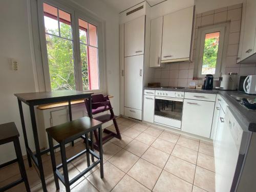 a kitchen with white cabinets and a table and chairs at Chez Carole (4 pièces) in Neuchâtel