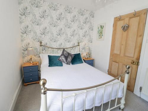 a bedroom with a white bed with blue pillows at Havens End in Conwy