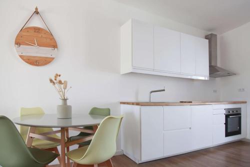 a kitchen with white cabinets and a table and chairs at Casa Biota in Sagres
