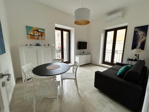 a living room with a black couch and a table and chairs at Palazzo Sandù Dimora nel Borgo in San Nicola Arcella