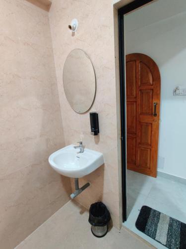 a bathroom with a sink and a mirror and a door at Hotel MJ baga in Calangute