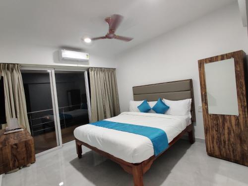 a bedroom with a bed with blue pillows at Hotel MJ Beach Resort Baga in Baga