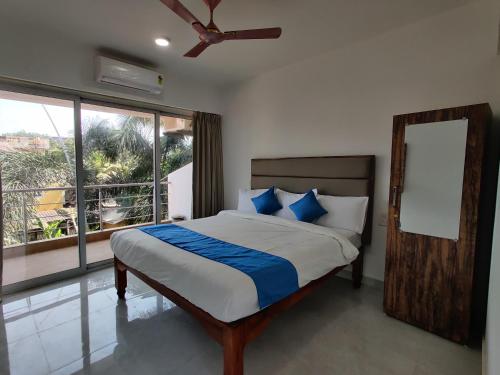 a bedroom with a bed with a ceiling fan and a window at Hotel MJ baga in Calangute