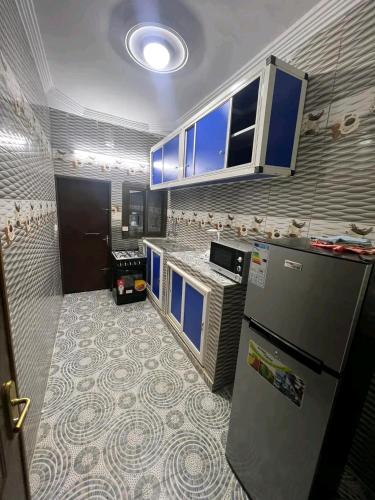 a kitchen with blue cabinets and a refrigerator at As résidence meubles E p in Ouagadougou