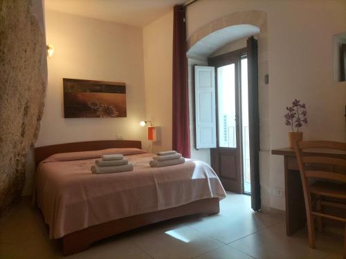 una camera da letto con un letto e asciugamani di San Filippo Neri - CAMERE a Ragusa