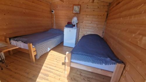 a bedroom with two beds in a wooden cabin at SP camping Spāres Prieduļi in Nīca