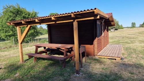 a wooden shelter with a picnic table in a field at SP camping Spāres Prieduļi in Nīca