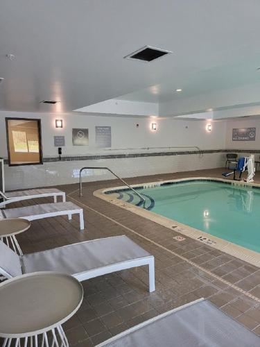 een groot zwembad met stoelen en een tafel en een tafelblad bij Spark by Hilton Erie in Erie