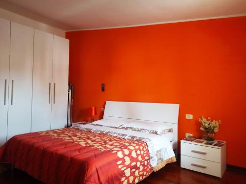 Un dormitorio con una pared de color naranja y una cama en Appartamento Piazza Dante Alighieri en Grosseto