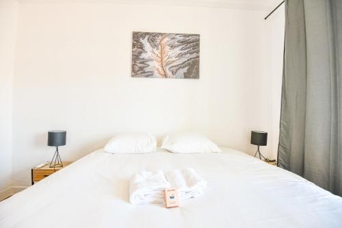 une chambre avec un lit blanc avec deux serviettes dessus dans l'établissement Vieux-Port - Vue exceptionnelle - 2 ch et clim, à Marseille