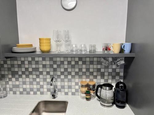 una encimera de cocina con fregadero y vasos en un estante en Trendy Green Point Retreat, en Ciudad del Cabo