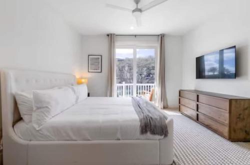 a white bedroom with a large bed and a television at Ocean Retreat Pool, Bbq, Short Walk To Beach in Saint Augustine Beach