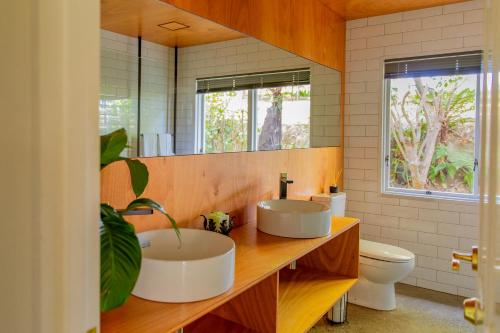 uma casa de banho com 2 lavatórios e um WC em The House - The Lodge Te Horo em Te Horo