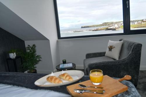 a table with a plate of bread and a glass of orange juice at Shoreline Portballintrae North Coast Views Near Giants Causeway & Royal Portrush in Portballintrae