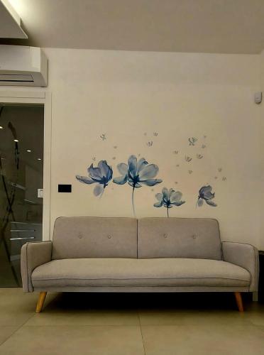 a couch in a living room with blue flowers on a wall at Sapore di sale in Grottammare