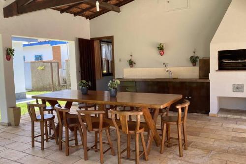 uma grande cozinha com uma mesa de madeira e cadeiras em Primavera Acolhedora em Holambra