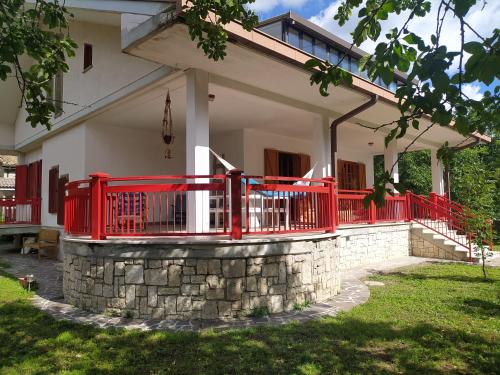 una casa con una recinzione rossa e un muro di pietra di Casa BnB Pappappero Monti della Laga a Fioli
