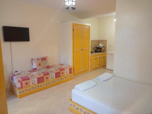a bedroom with two beds and a flat screen tv at Dar Bouanani in Asilah