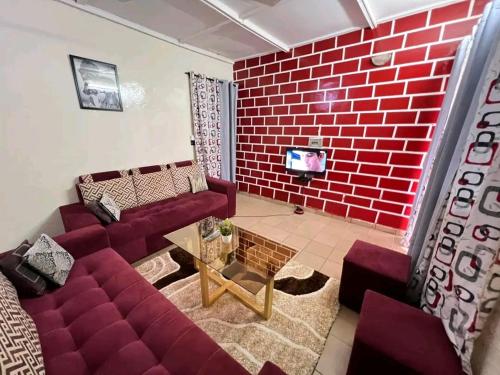 una sala de estar con una pared de ladrillo rojo en As résidence meubles k, en Ouagadougou