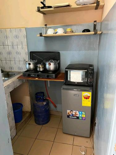 una pequeña cocina con microondas encima de una nevera en As résidence meubles k, en Ouagadougou