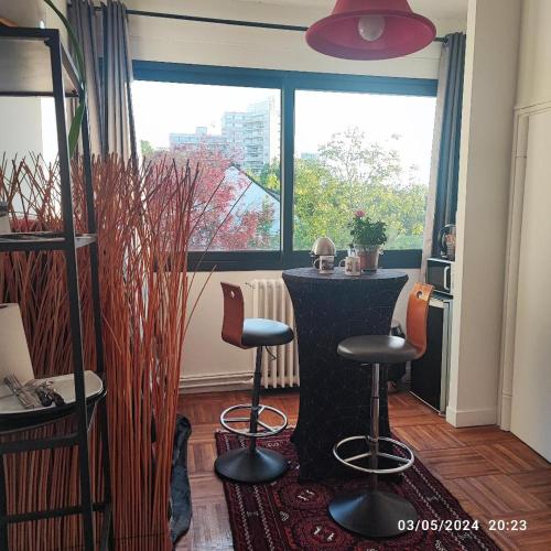 una stanza con un tavolo e due sgabelli di fronte a una finestra di Chambre spacieuse avec terrasse dans villa d architecte a Le Pecq