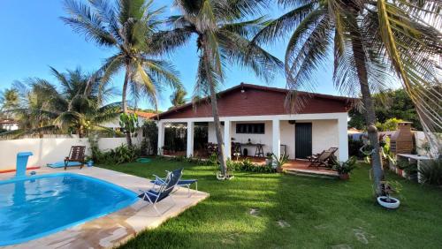 a house with a swimming pool and palm trees at Espaço Brilho do Sol Genipabu in Extremóz