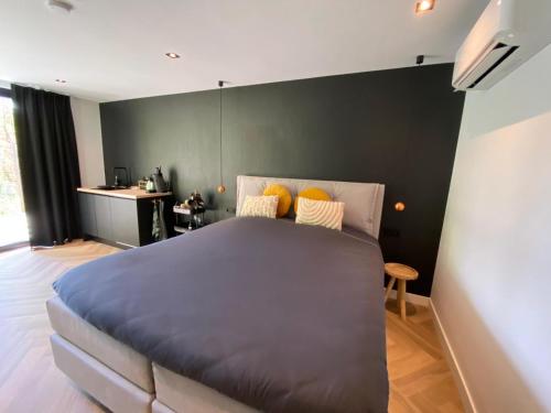 Un dormitorio con una gran cama azul con almohadas amarillas en BnB Paradijs Oude Niedorp, en Oude-Niedorp