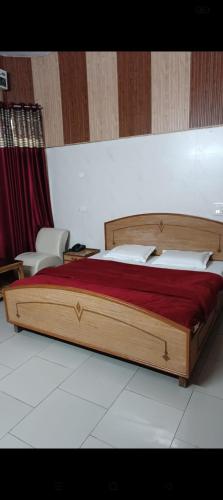 una camera da letto con letto in legno, lenzuola rosse e cuscini bianchi di Hotel Batra a Ludhiana