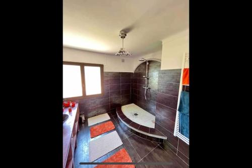 une salle de bain avec des murs carrelés marron et une fenêtre dans l'établissement Élégance Villa à Saint-Raphaël, à Saint-Raphaël