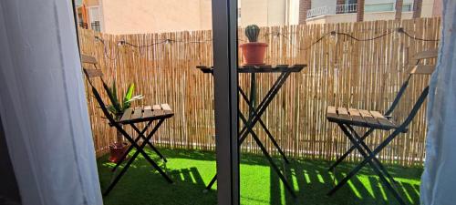 eine Terrasse mit 2 Stühlen, einem Tisch und einem Zaun in der Unterkunft Apartamento en el centro de Elche con terraza in Elche