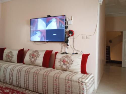 a living room with a couch with a tv on the wall at حي الهناء 2 in Rouamcha