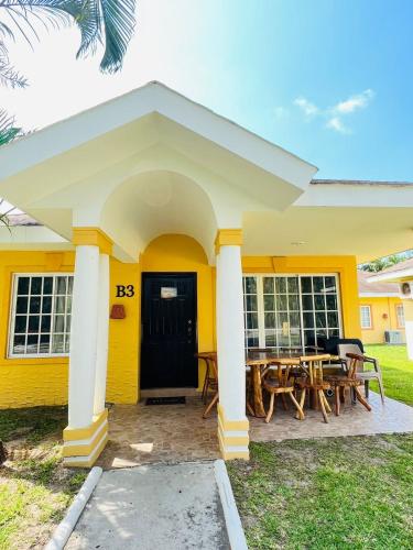 una casa amarilla con una mesa delante en villa en palma real, en La Ceiba