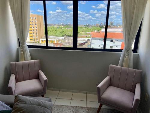 two chairs in a room with two large windows at Apartamento em Mossoró com 2 quartos, piscina e garagem in Mossoró