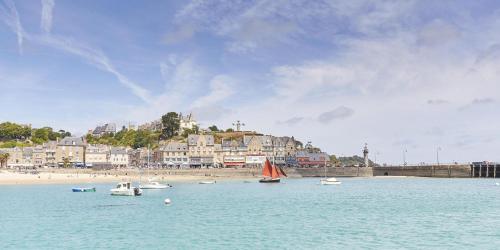 Un grupo de barcos en el agua cerca de una playa. en T2 Rez-de-chaussée, Le Victor Hugo, en Cancale