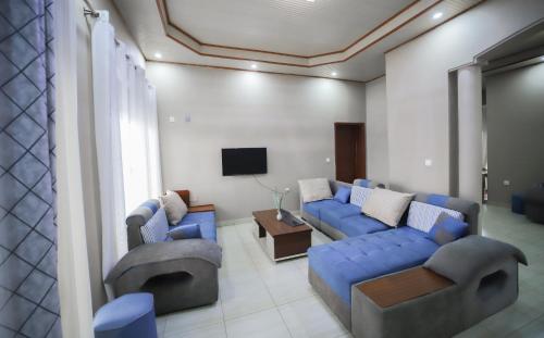 a living room with blue couches and a tv at OMX Hotel Remera in Kigali