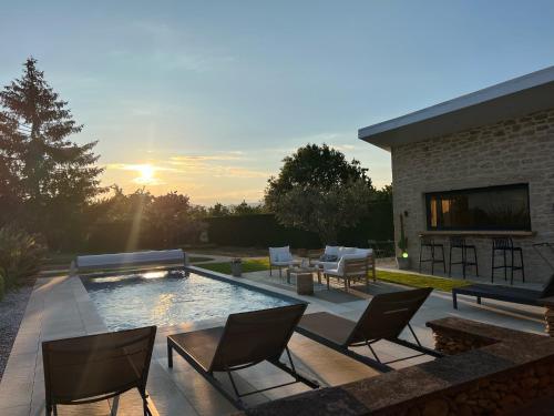 un patio avec des chaises et une piscine avec vue sur le coucher du soleil dans l'établissement La parenthèse, à Aubérives-sur-Varèze