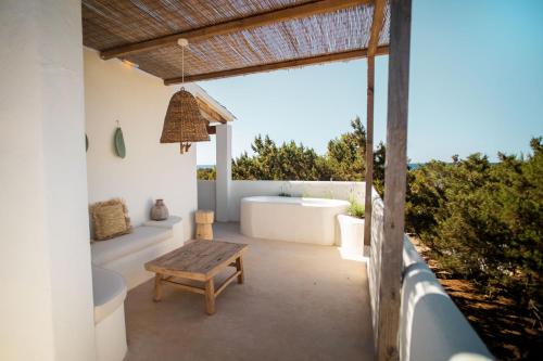 uma casa de banho com uma banheira, uma mesa e um banco em Estel Formentera em Es Migjorn