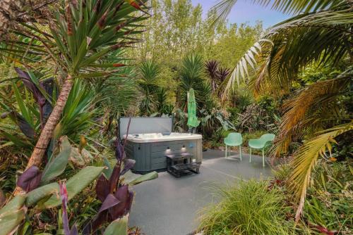 eine Terrasse mit 2 Stühlen und einem Schreibtisch im Garten in der Unterkunft Swiss-Kiwi Retreat A Self-contained Appartment or a Tiny House option in Tauranga