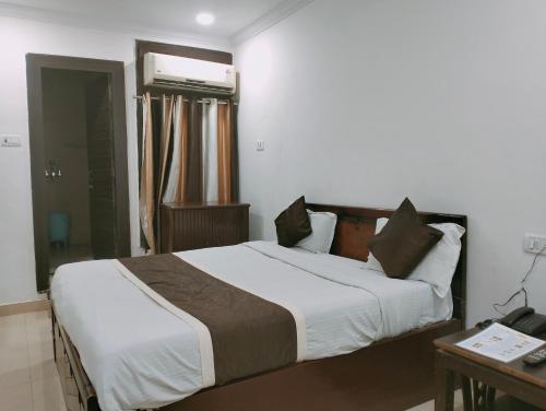 Hotel Maxx في لاكناو: غرفة نوم بسرير كبير وطاولة