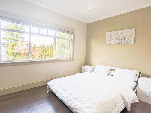 een slaapkamer met een wit bed en een raam bij Beautiful Private Room in BlueBack BeachFront in Nanaimo