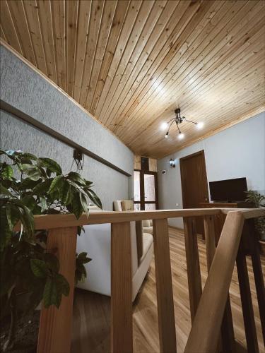 a living room with a wooden ceiling and a staircase at Guest House Nikala in Mestia