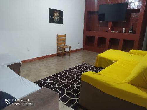 uma sala de estar com um sofá amarelo e uma televisão em Hostel Pantanal Experience - Pantanal n' Bonito Tours em Campo Grande